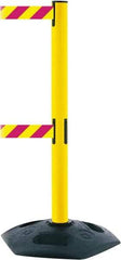 Tensator - 38" High, 2-1/2" Pole Diam, 4 Way Stanchion - 19" Base Diam, Octagon Recycled Rubber Base, Yellow Plastic Post, 7-1/2' x 2" Tape, Dual Line Tape, For Outdoor Use - Eagle Tool & Supply