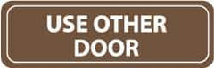 NMC - Use Other Door, 11" Wide x 3.5" High, Acrylic Sign - English, White on Brown, Wall Mount - Eagle Tool & Supply
